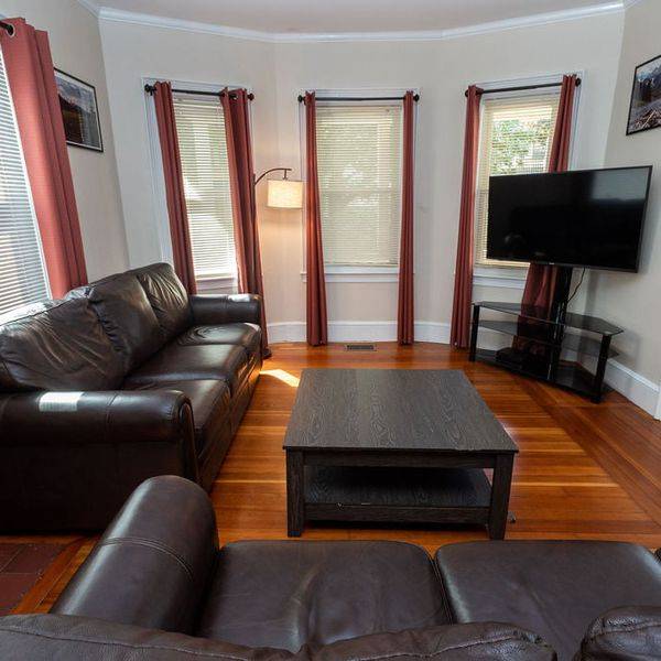 Living room with brown leather sofas, a coffee table and a wall-mounted television.