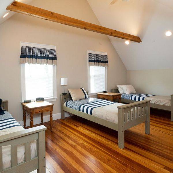 Upstairs bedroom with a wooden bed, blue striped bedding and a sloped ceiling.