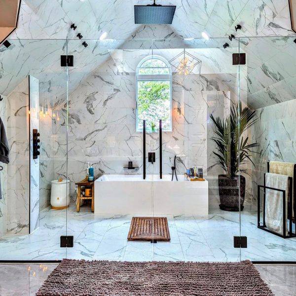 Bathroom with marble walls, a soaking tub and a glass-enclosed shower.