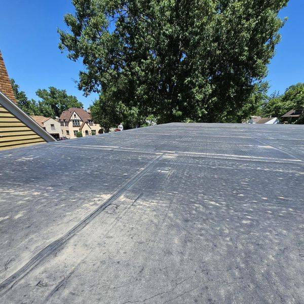 Close view of a dark flat roof membrane with seams across the surface.