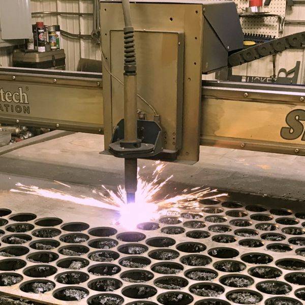 Plasma cutter cutting a pattern of round holes through heavy steel plate
