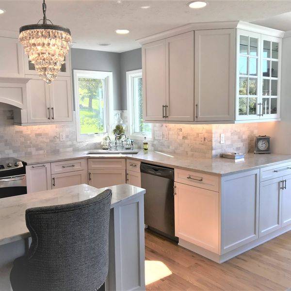 Bright kitchen with cream cabinets, a marble backsplash and a window over the sink.