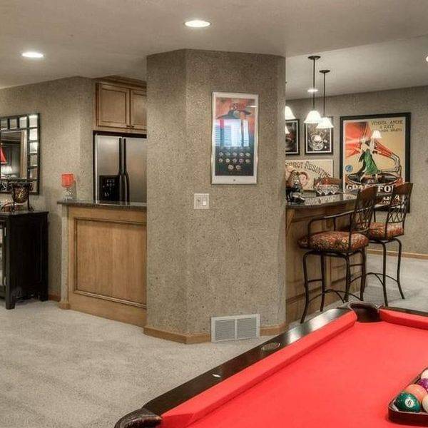 Basement bar area beside a red pool table with framed posters on the wall.