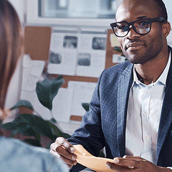 A mortgage advisor in a blazer listening to a client across a desk.