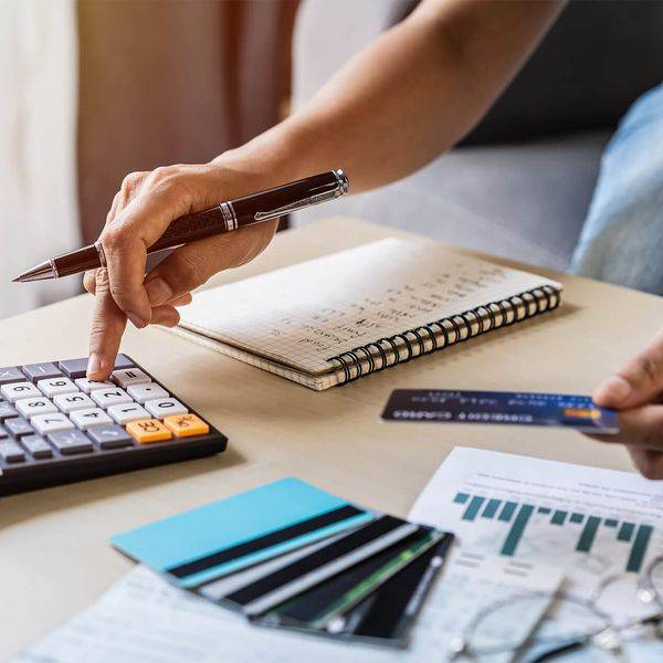 Hands working through loan paperwork with a calculator, pen and credit cards.