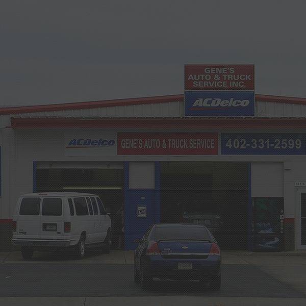 Front of the red shop building with a van and a sedan parked out front.