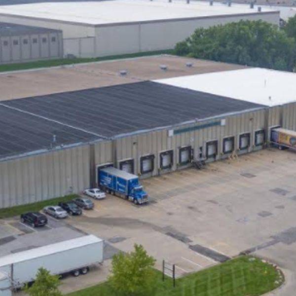 Aerial view of a large warehouse with loading docks and trucks parked outside.