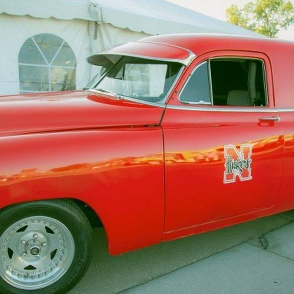 Restored red vintage delivery van parked outside a building.