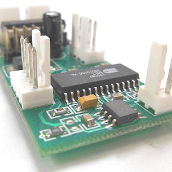 Close-up of a green circuit board with chips and white connector headers.