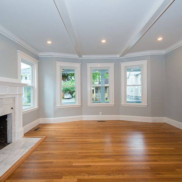 Bright living room with a fireplace, bay windows and light wood floors.