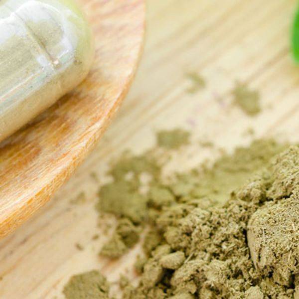 Powdered herbal material sits on a wooden surface beside a small bowl.