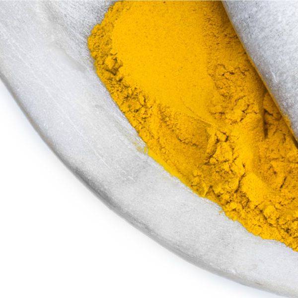 A white mortar holds bright yellow powder in a close-up view.