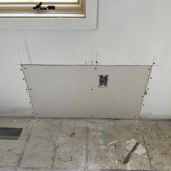 Drywall panel being fixed into an opening in a room with tile floor.