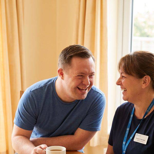 A man and a woman laughing together over coffee at a wooden table.