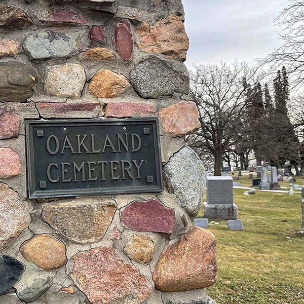 Stone entrance sign reading Oakland Cemetery set into a stone wall on the grounds.