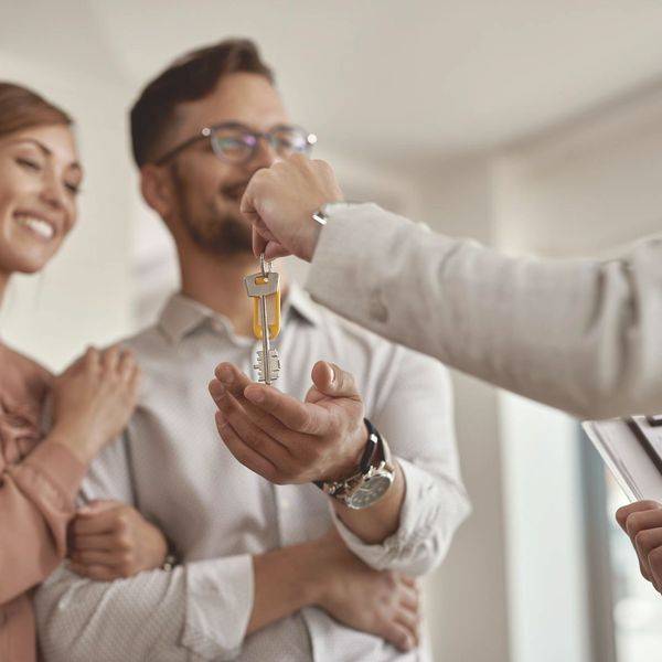 Smiling couple in a bright room receiving a set of house keys.