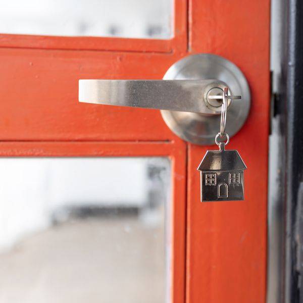 Orange door with a silver handle and a small house-shaped key ring.
