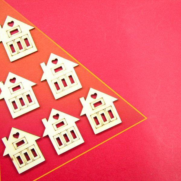 Small wooden house figures arranged on a red background.