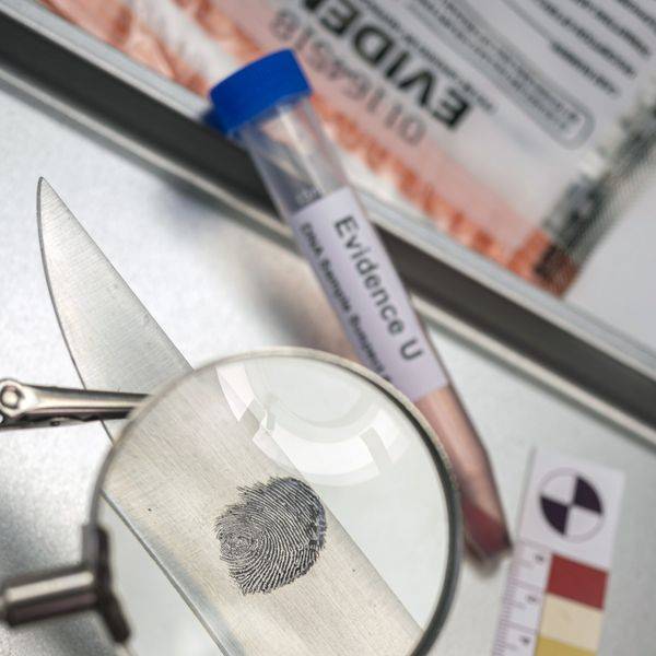 Close view of a fingerprint under a magnifying glass beside evidence markers.