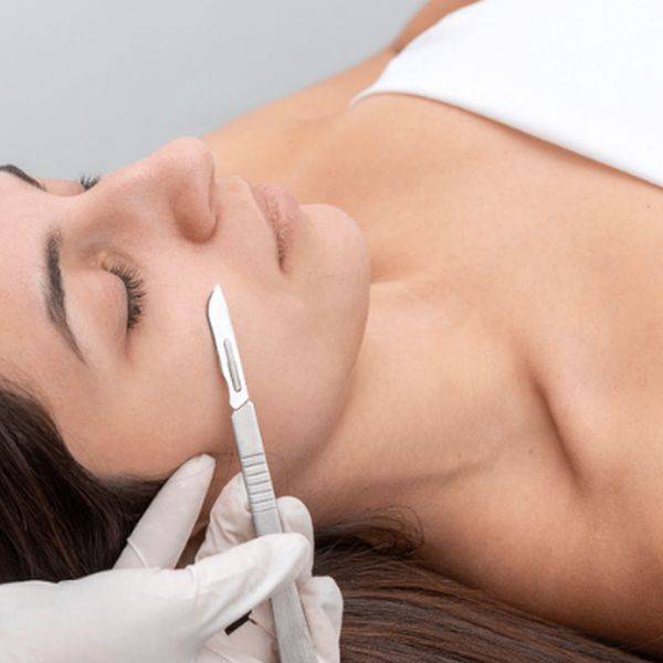 Close view of a client lying face up during a facial treatment with a tool near the cheek.