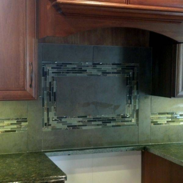 Kitchen backsplash of glass and stone mosaic tile above a dark countertop.